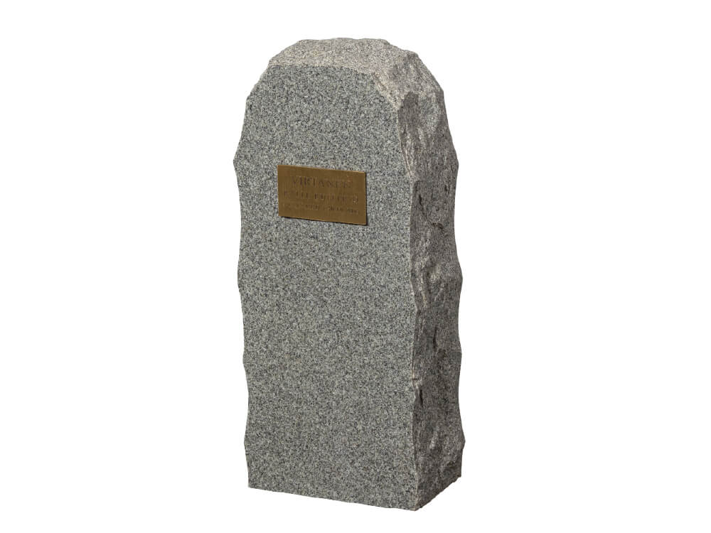 Kapea ja korkea harmaapilkullinen kivi, sivut lohkotut, pieni messinkinen nimilaatta.Hautauspalvelu Kaiho - Hautakivet