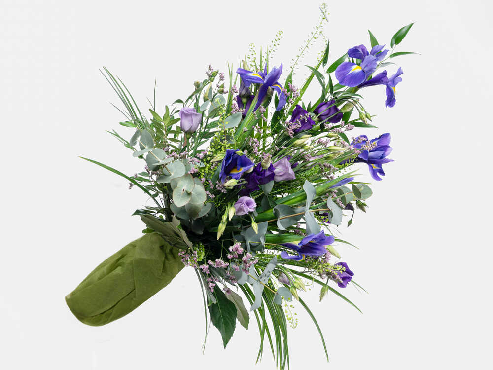 Rönsyilevä kukkakimppu, jossa on runsaasti violettia iiristä, lilaa eustomaa ja erilaisia vihreitä.